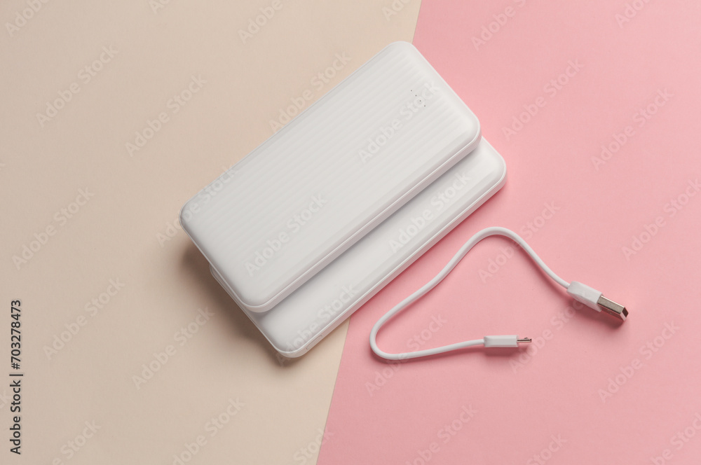 White power banks with cable on pastel background. External batteries for charging smartphone and other gadgets. Top view White power banks with cable on pastel background. External batteries for charging smartphone and other gadgets. Top view