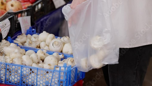 Shooper collecting fresh muschrooms with a plastic bag at a local market photo