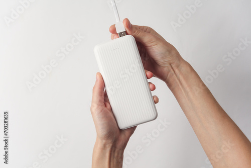 Hands holding white external battery power bank on white background