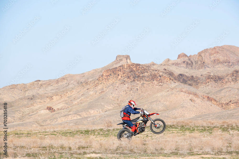 A motorcyclist rides on a wheelie. Mountain, cross-country motorcycle on the rear wheel. Extreme sports in the desert. A motorcyclist rides on a wheelie. Mountain, cross-country motorcycle on the rear wheel. Extreme sports in the desert.