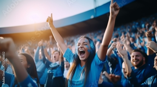 group of fans dressed in blue color watching a sports event in the stands of a stadium