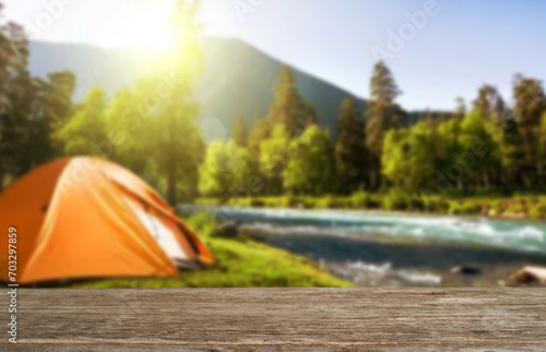 Wooden table top on blur tent camping travel tent and grass field.Fresh and Relax concept.For montage product display or design key visual layout.View of copy space.