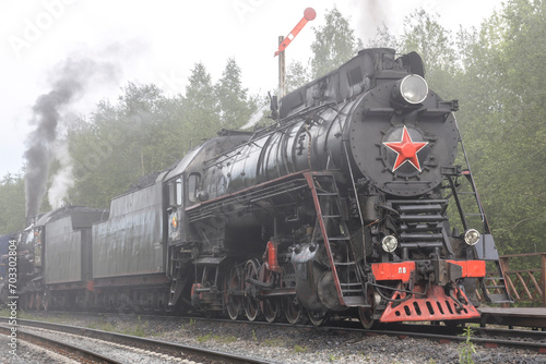 View of an approaching classic steam locomotive with the Soviet emblem