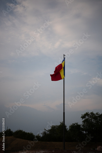 Romanian national Flag in wind in background with beautiful blue sky