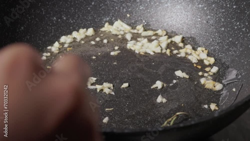 Chef Frying Garlic with Rosemary In Oil On Non-stick Pan. - close up shot