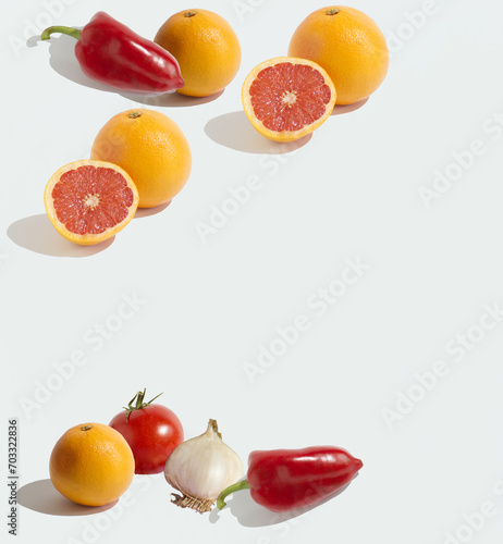 A natural pattern made of isolated grapefruits, a tomato, a garlic, peppers and oranges on a white background. Copy space, minimal food concept. Healthy nutrition.