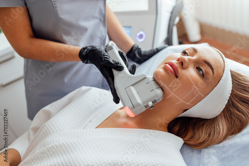 Portrait of relaxed young female client getting SMAS ultrasound face lifting massage photo