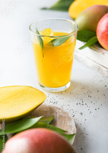 Fresh mango juice and glass with ice cubes and fresh raw fruits.
