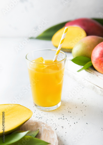 Fresh mango juice and glass with ice cubes and fresh fruits.