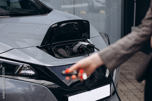 Woman holding socket and charging electric car