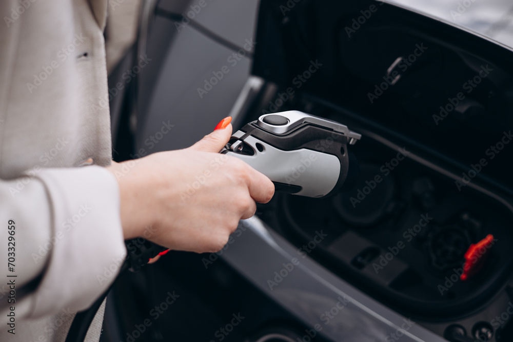 Woman charging electric car at charging station