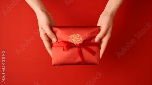 A red envelope, vertical style, holding by hand isolated on red background. Hongbao packet for lucky money gift in Chinese lunar, new year on January month, wedding red packet.