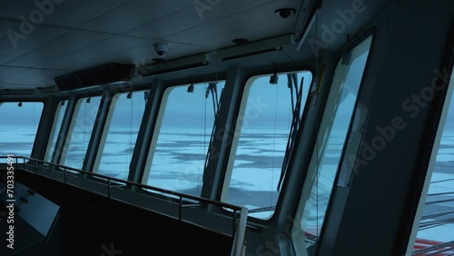 Vessel in ice. View from navigation bridge through big windows. Frozen sea outside.