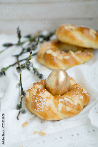 Easter buns nest shaped with golden egg on top with white natural background close up selective focus
