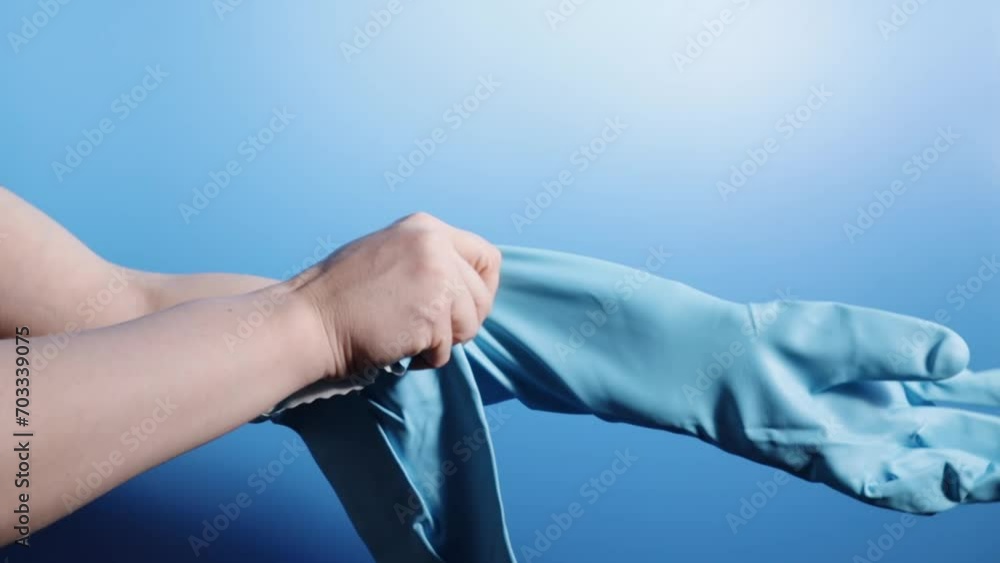 cleaner puts cleaning gloves on his hands on a blue background cleaner puts cleaning gloves on his hands on a blue background