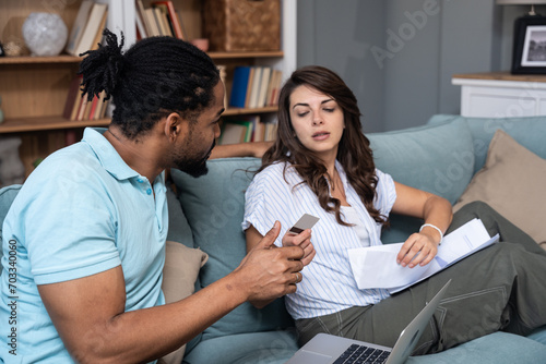 Young couple man and woman, roommates sitting at home on sofa having issue with financial debt, overspending and earnings, cant pay the bills. Online banking problems, over limit usage concept