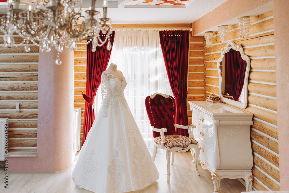 Bedroom interior with wedding dress prepared for the ceremony. A beautiful lush wedding dress on a mannequin in a hotel room. Bedroom interior with wedding dress prepared for the ceremony. A beautiful lush wedding dress on a mannequin in a hotel room.