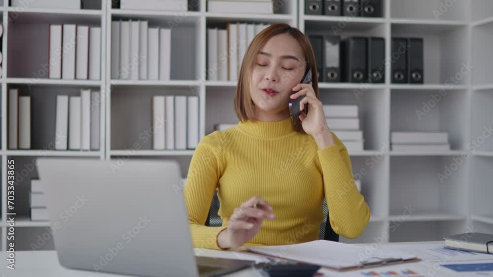 Businesswoman is talking to clients and colleague on the phone and working on laptop in office Businesswoman is talking to clients and colleague on the phone and working on laptop in office