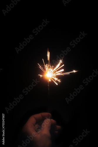 sparkler on black background, holds in hands