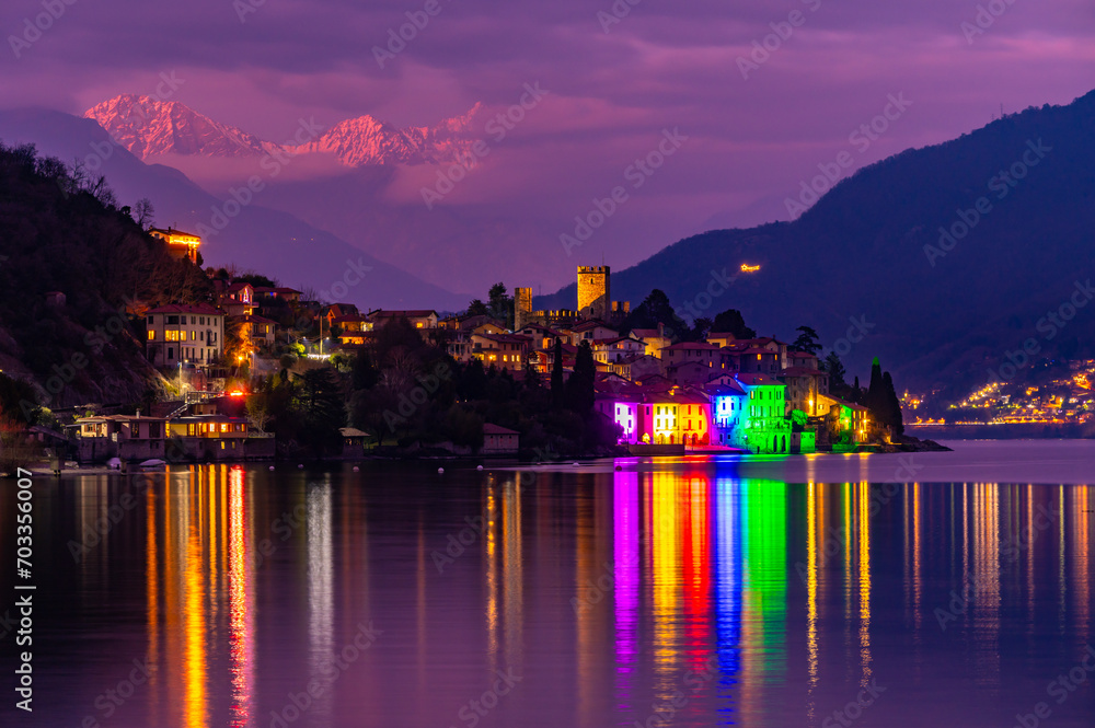 The town of Santa Maria Rezzonico, on Lake Como, photographed on a winter evening, with its tower and the snow-capped Alps in the background.
