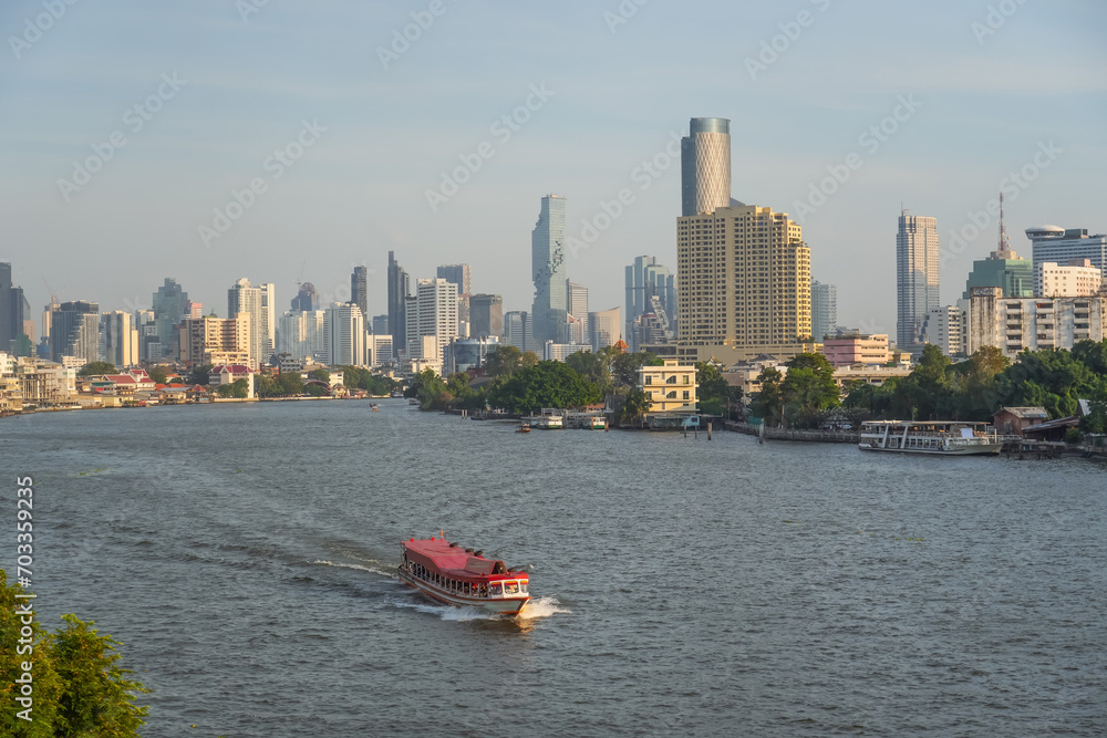 Fototapeta premium Boat ship traffic and tourist taking river cruise on Chao Phraya with skyscraper view sunset time In Bangkok, Thailand.