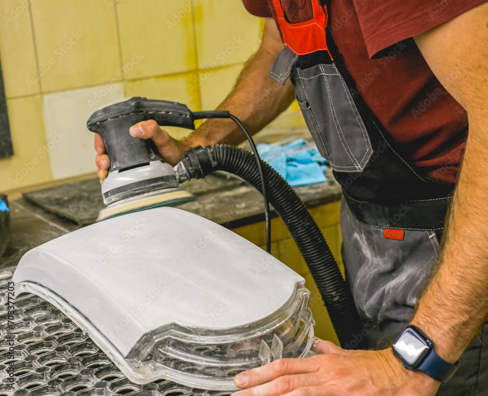 Fototapeta premium Restoration of the headlight glass using a grinding machine. A man polishes the optics of a car's headlights with a polishing machine at a service station. Hands working with a polishing machine.