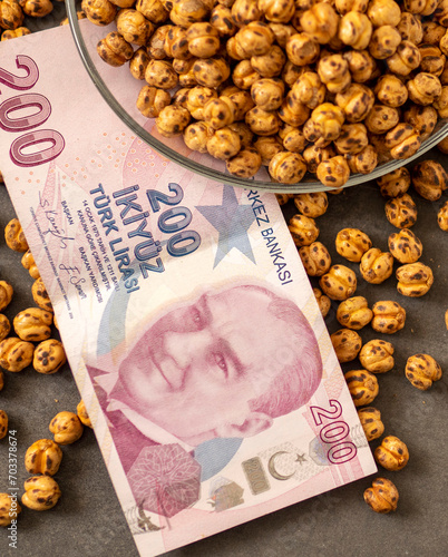 Close-up of a plate full of Turkish roasted chickpeas and 200 Turkish liras next to it, implying that the prices of roasted chickpeas are increasing. © kodbanker