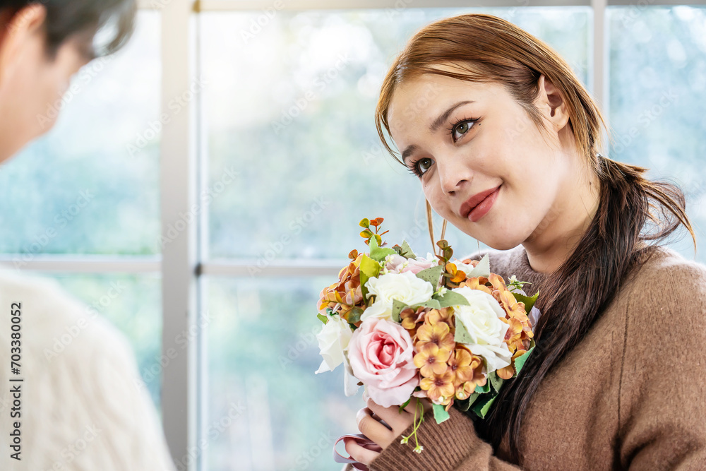 Asian young man surprising his beautiful girlfriend with bouquet of flowers at home, Attractive romantic new marriage couple male and woman spend time to celebrate anniversary and valentine's day Asian young man surprising his beautiful girlfriend with bouquet of flowers at home, Attractive romantic new marriage couple male and woman spend time to celebrate anniversary and valentine's day