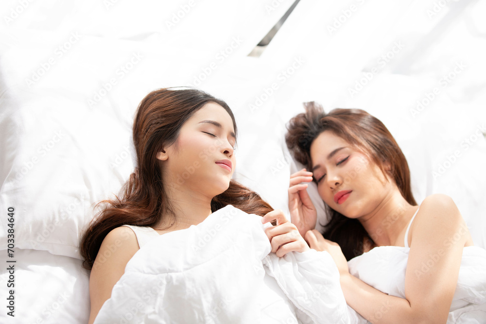 Asian LGBTQ lesbian woman cuddling on their bed at home.Lesbian couple love moments happiness , lovely lesbian couple spending time together and having fun in bed, LGBT concept.