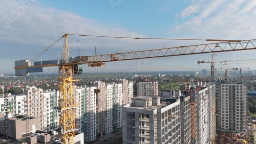 Aerial view at the construction site of a multi-story apartment building. In the frame tower crane and unfinished real estate
