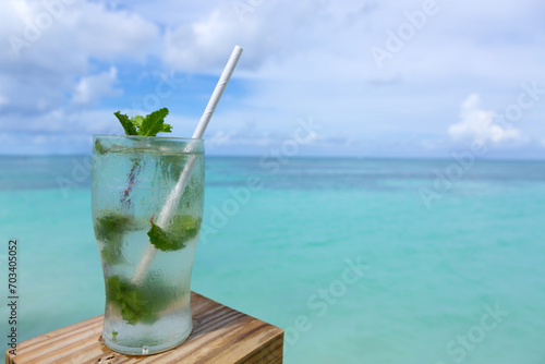Travel background with drinks glass and straw on Caribbean beach.