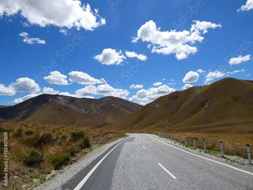 Entering Lindis Pass, linking Mackenzie Basin with Central Otago. South Island of New Zealand. View over road with mountains in the background.