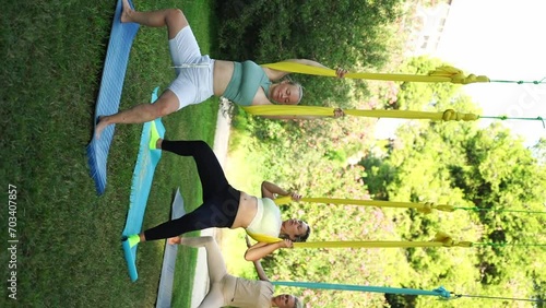 Women workout together outside in public park. Yoga and Stretching in hammocks. Sport for women health. Exercises aid reducing stress, maintaining harmony within, and contribute to overall wellbeing photo