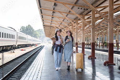 Two Asian female tourist friends are at the train station. Waiting for the train to travel to the provinces together on the weekend. © wichayada