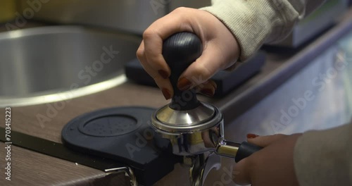 Coffee barista tamping compressing grinds in puck before extraction photo