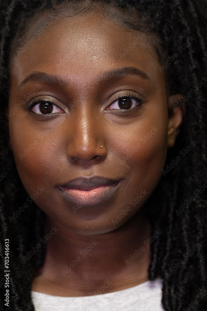 This striking portrait captures a young Black woman, her eyes speaking volumes beneath a calm and measured gaze. The natural lighting softly defines her facial features, highlighting her rich skin This striking portrait captures a young Black woman, her eyes speaking volumes beneath a calm and measured gaze. The natural lighting softly defines her facial features, highlighting her rich skin