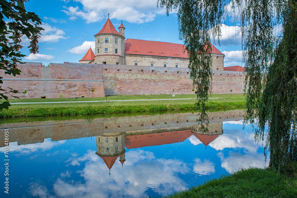 Fototapeta premium Medieval fortress reflecting in water, summer landscape