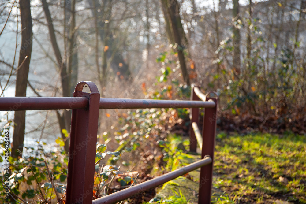An iron fence covered with rust and meadow in the background An iron fence covered with rust and meadow in the background