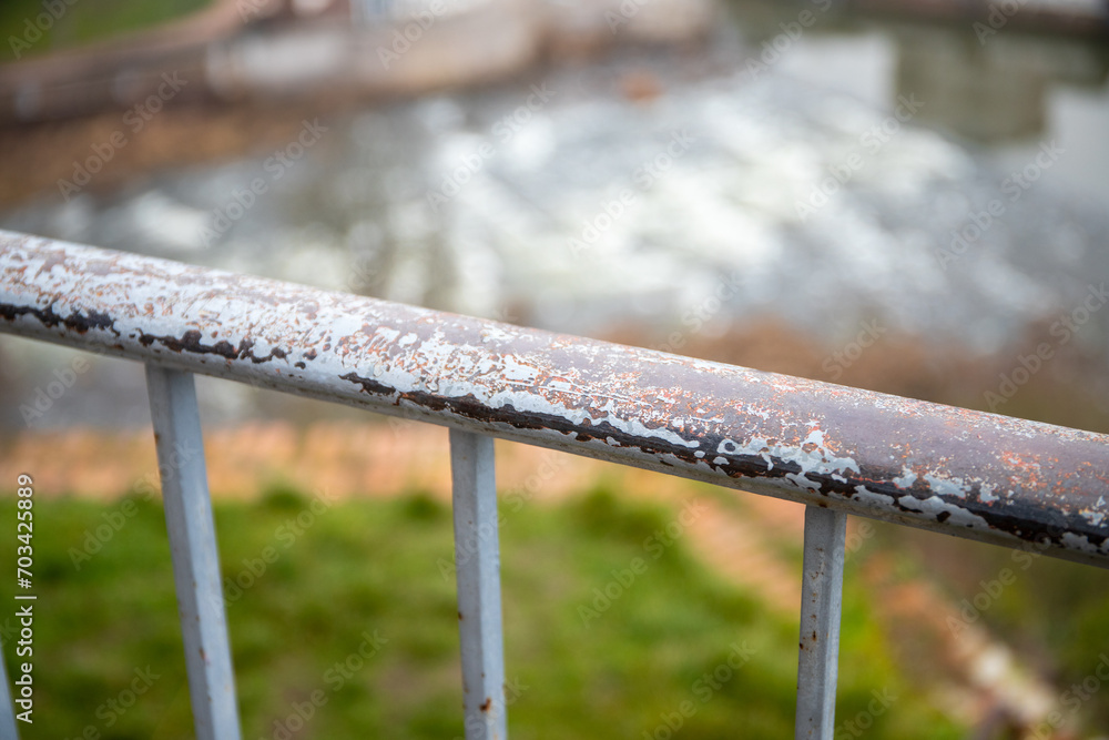 An iron fence covered with rust and meadow in the background An iron fence covered with rust and meadow in the background