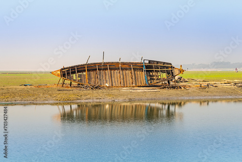 Repairing a wooden boat on the riverbank in Bangladesh.