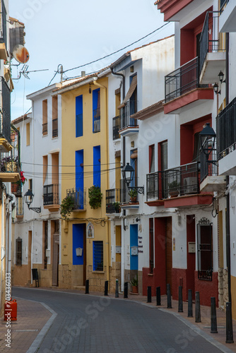 Empty narrow street view with colorful building facades in the old town of La Nucia in the province of Alicante, on the Costa Blanca, Spain photo