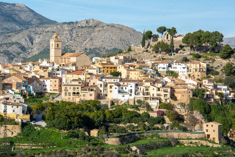 View of the town of Polop de la Marina with medieval fortress of Muslim origin and the Church of San Pedro and the high mountains at the back in Marina Baixa, Alicante, Spain