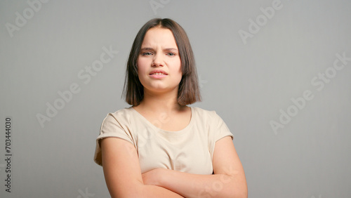 Picture of angry young latin woman standing isolated over gray background. Looking at camera
