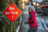Be active concept image with an old elder active woman and board sign with written words Be active to encourage elderly people to move and do sports and activities