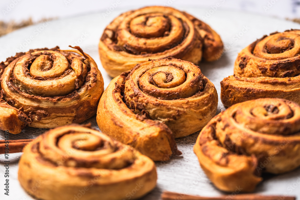 Closeup of homemade cinnamon rolls on white plate on white marble background