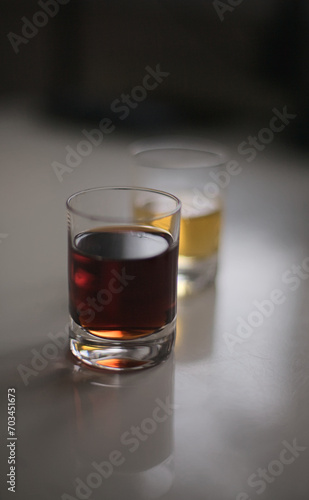 Two small glasses filled with red and yellow drinks