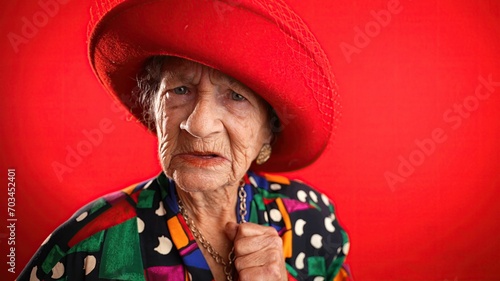 Unhappy displeased fisheye portrait caricature of funny elderly woman saying NO with red hat isolated on red background.