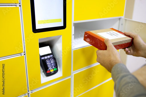 Close up of a man picks up mail from automated self-service post terminal machine photo