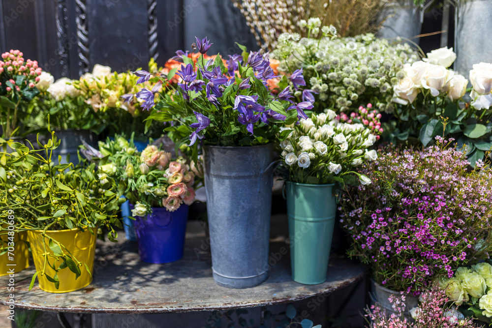 A variety of colors is near the flower shop. Large bouquets in tin vases.