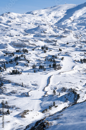 aerial view from a drone, of a high mountain ski slope, with many skiers, in the french pyrenees.
